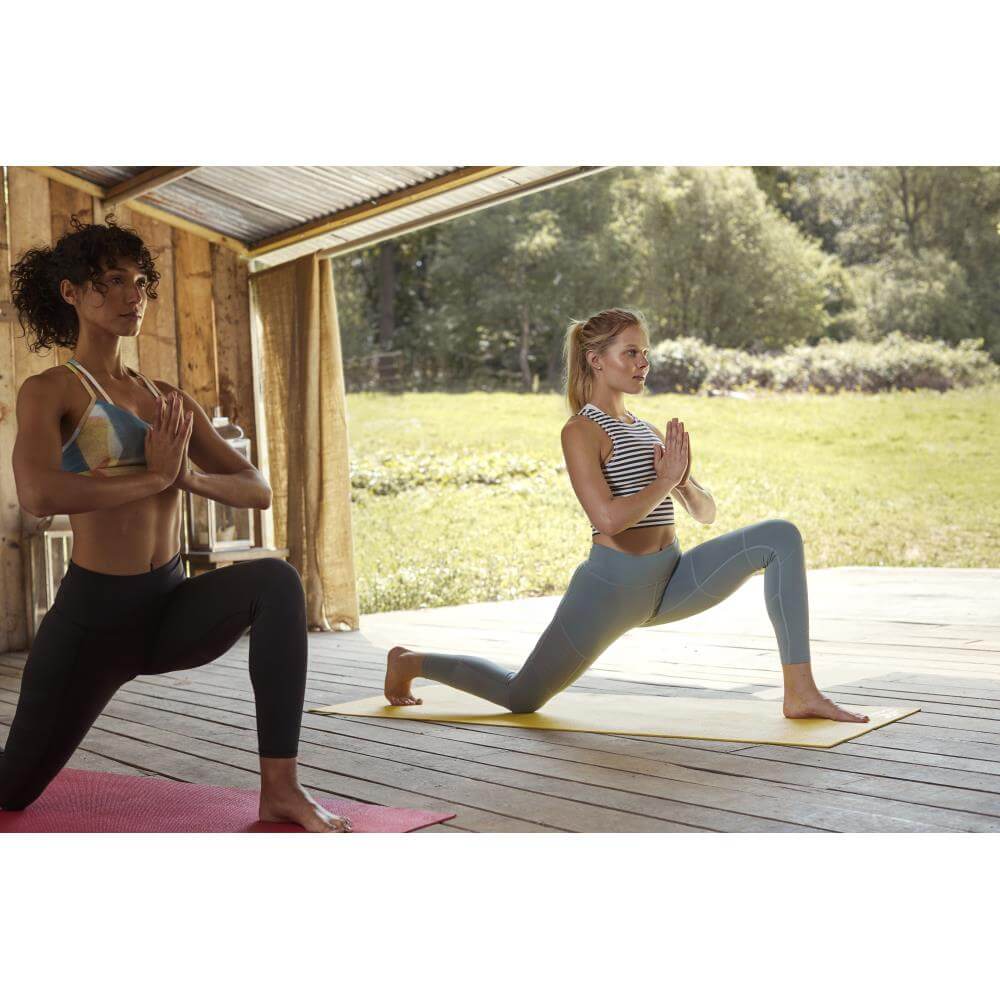 Two women doing a yoga pose on sReebok 4mm Yoga Mats - Yellow and red