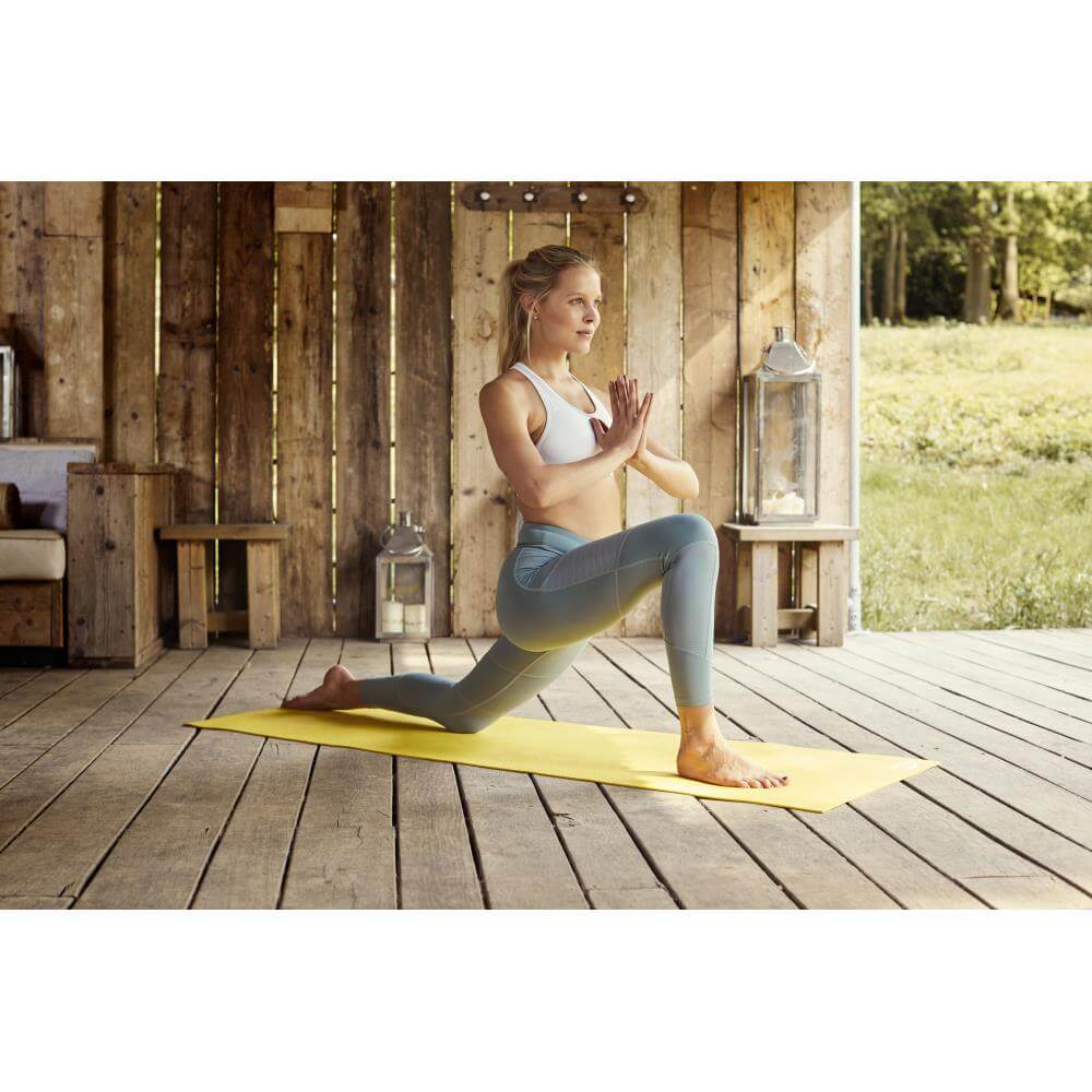 Woman doing a yoga pose on a Reebok 4mm Yoga Mat - Yellow
