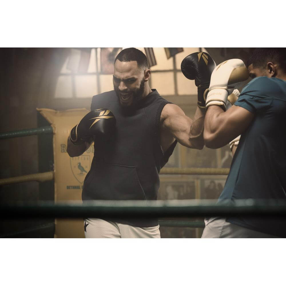 Two men boxing in a boxing ring with Reebok Boxing Gloves - Black and Gold