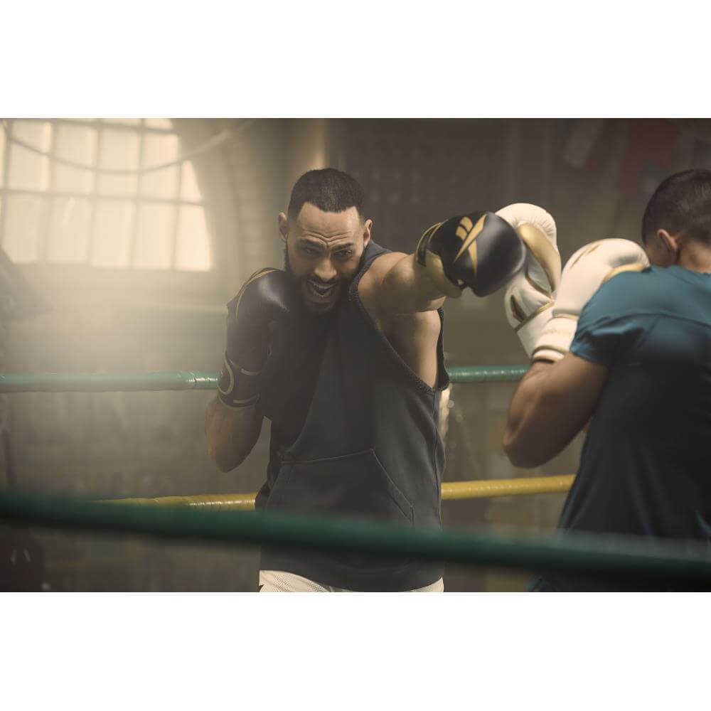 Two men in a boxing ring boxing wearing Reebok Boxing Gloves - Black and Gold 