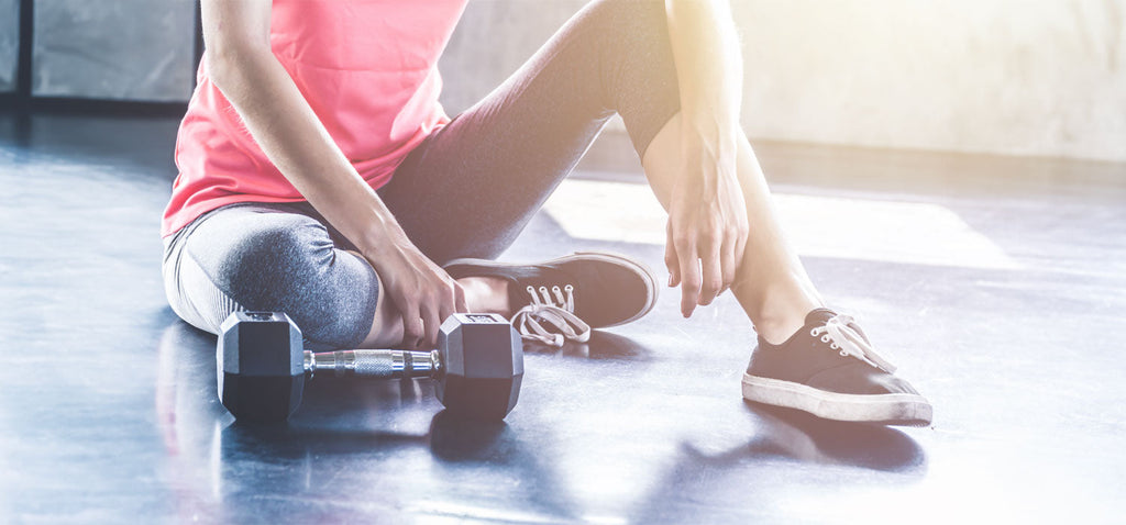 Woman sitting on the gym floor with a dumbbell