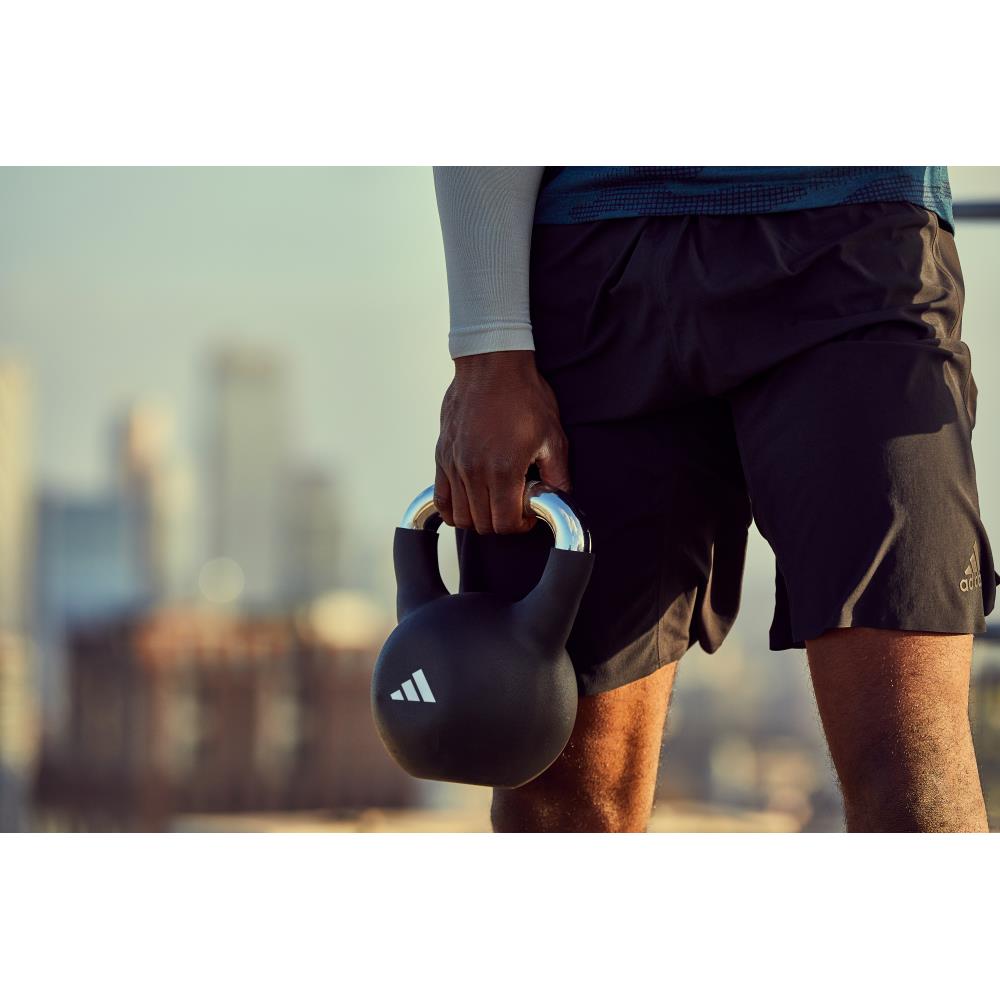 Person holding a black kettlebell with a blurred cityscape background