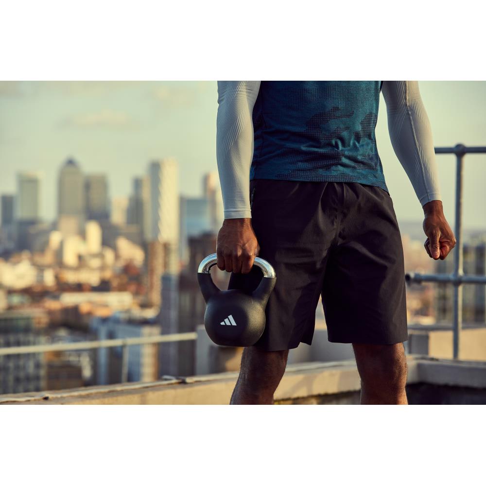 Person holding a 16kg adidas kettlebell with a cityscape in the background