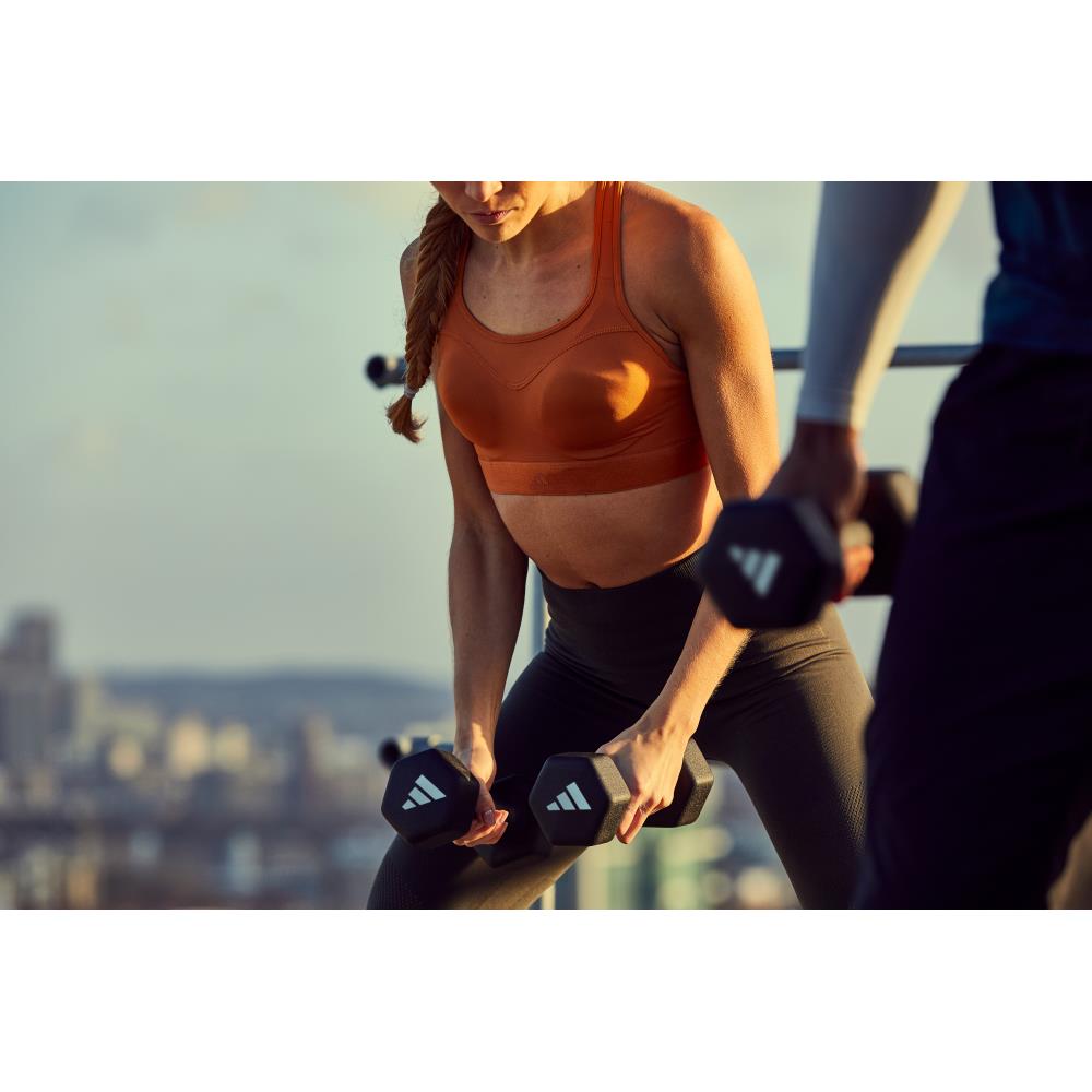 Woman exercising with dumbbells outdoors, blurred cityscape in the background