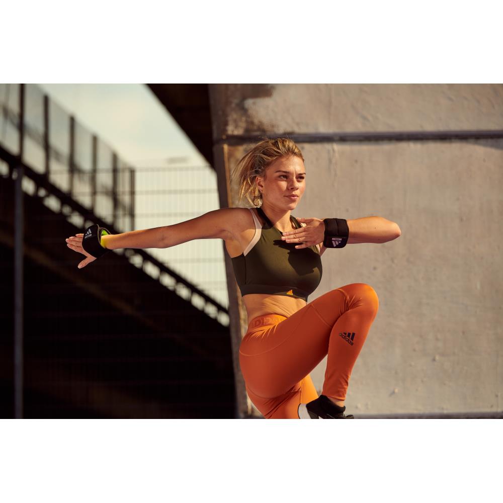 Woman in athletic wear training with the adidas ankle/wrist weights 0.5kg