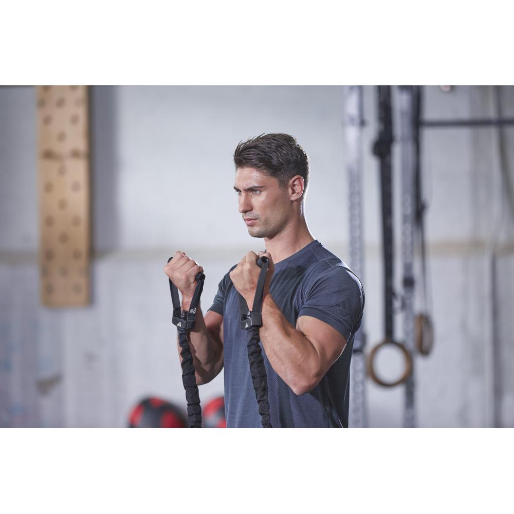 Man exercising with adidas resistance bands in a gym setting