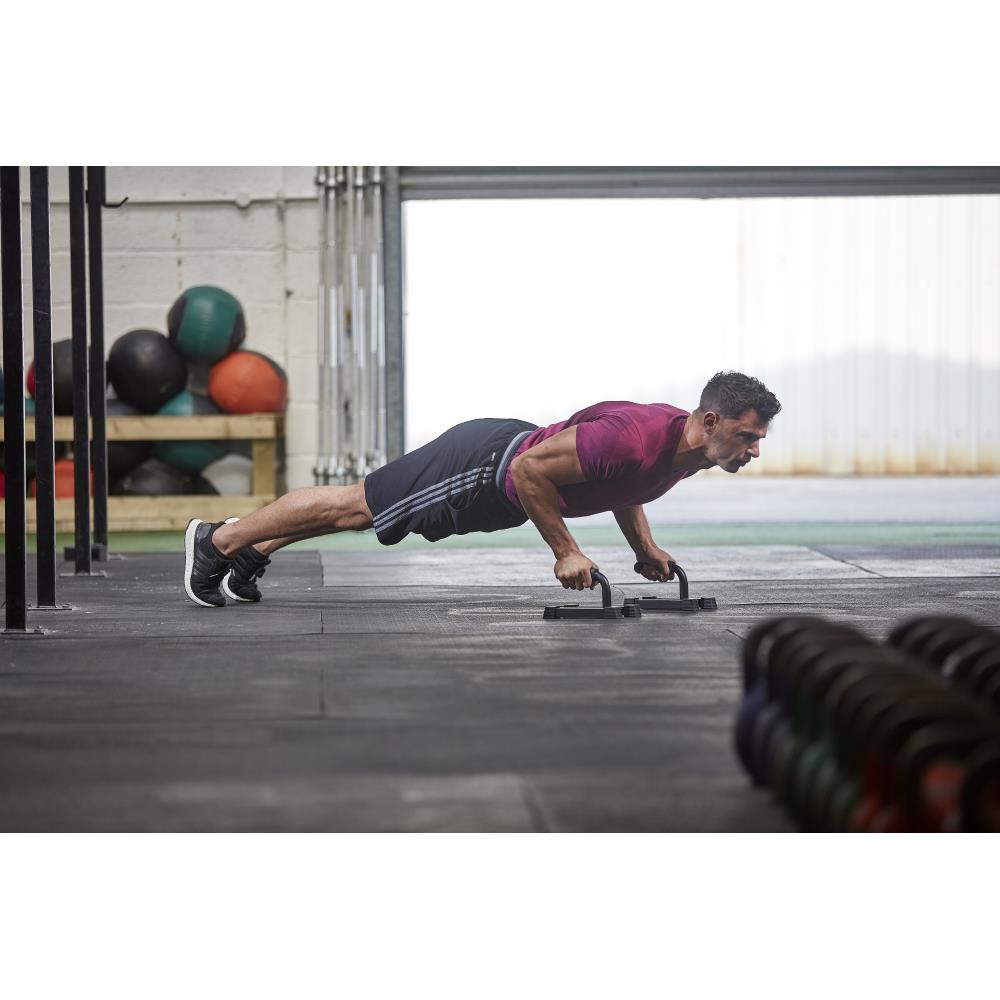 Person doing push-ups on a gym floor with fitness equipment in the background