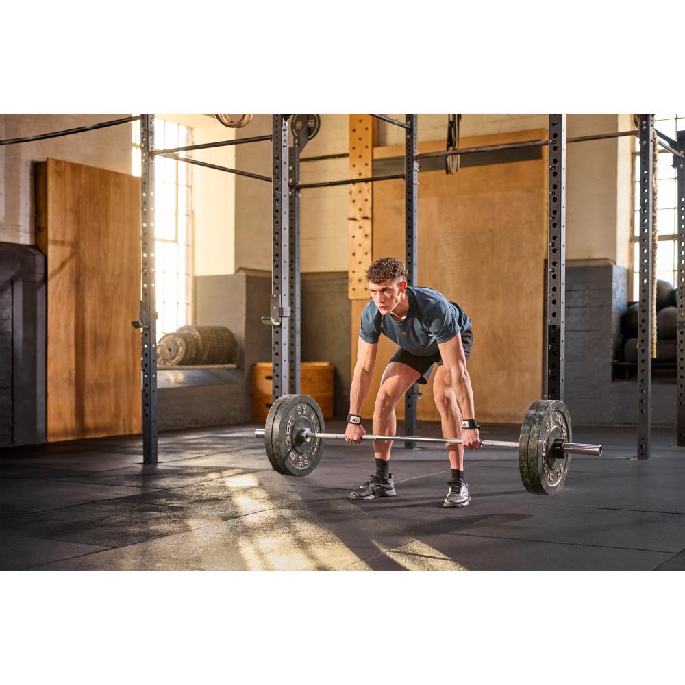 Man lifting a barbell in a gym setting wearing  adidas wrist wraps