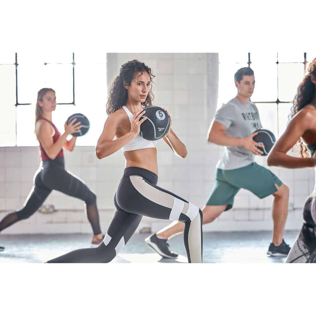 Group of people exercising with medicine balls in a fitness setting