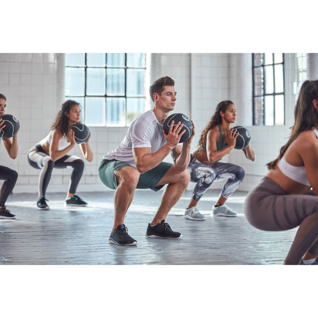 Group of people exercising with medicine balls at a gym class.
