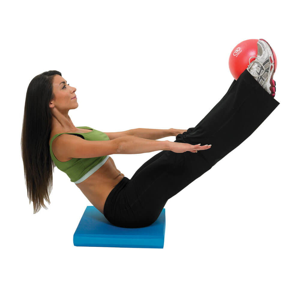 Woman sitting on a mat holding Fitness Mad 9 Inch Exer-Soft Ball between feet  - Workout