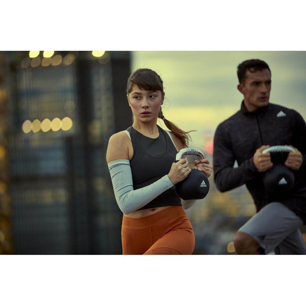 man and woman exercising with adidas 12kg kettlebells