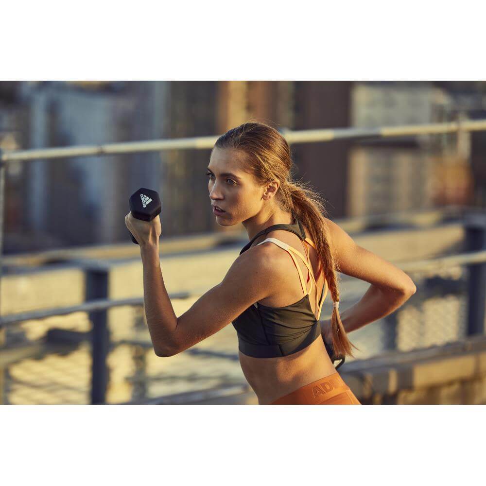 Woman performing resistance training holding adidas 1kg dumbbells
