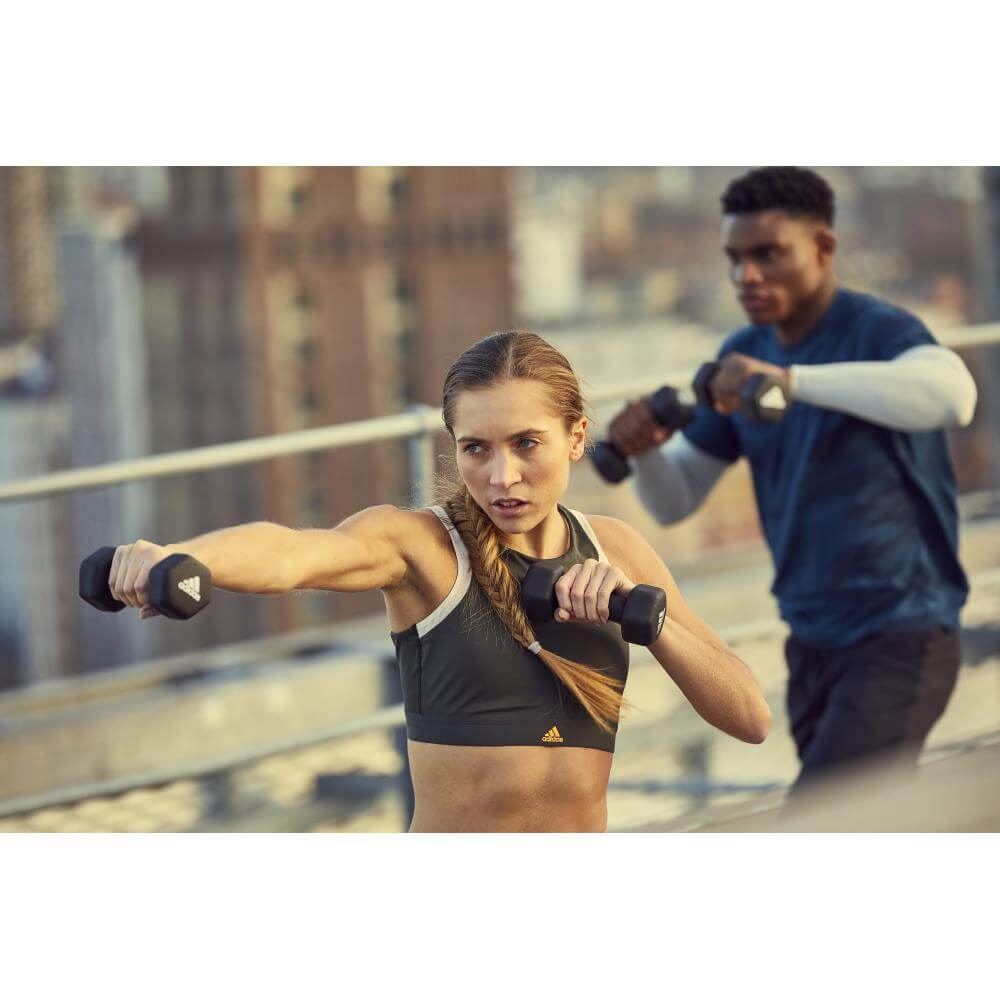 Man and woman performing resistance training holding adidas 2kg dumbbells
