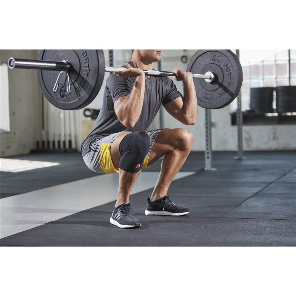 Man weight lifting whilst wearing an adidas Knee Support 