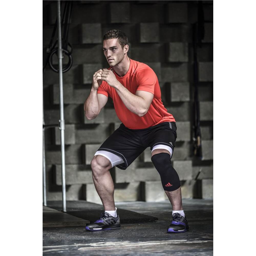 Man performing squats wearing an adidas Knee Support