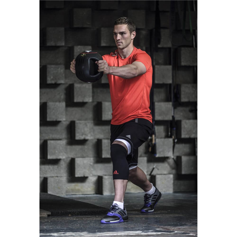 Man exercising with a slam ball whilst wearing an adidas Knee Support 