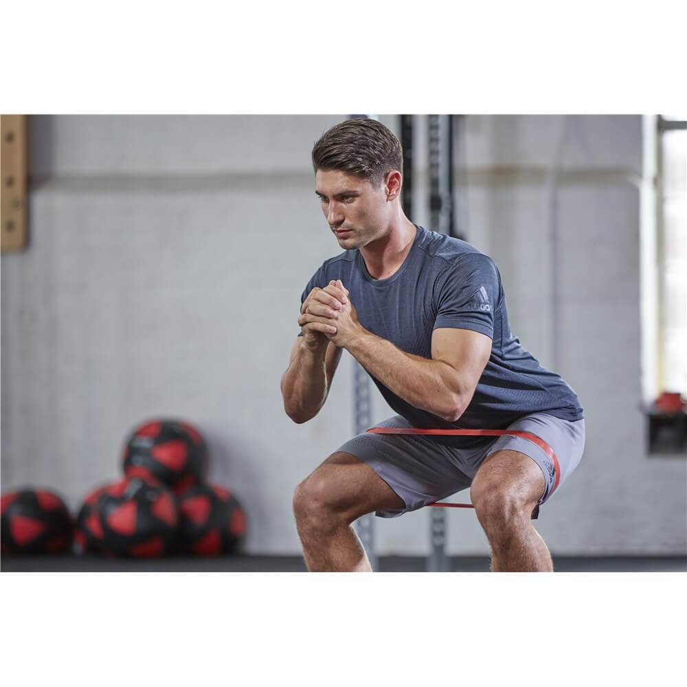 Man performing glute workout using Adidas Mini Loop Bands