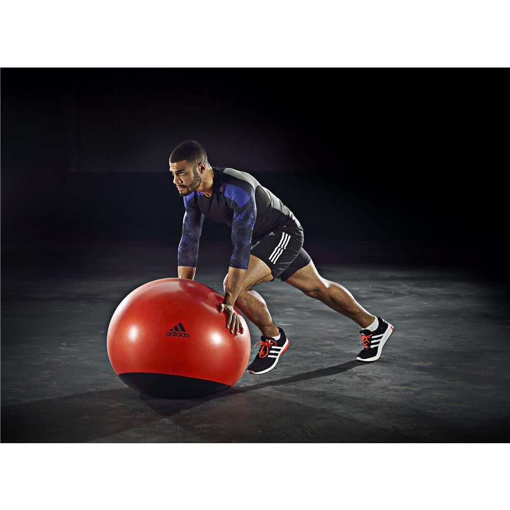 Man performing a fitness workout on an adidas Stability Gym Ball - 65cm, Orange 