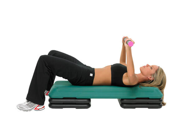 Woman exercising on a step platform whilst lifting a Fitness Mad 5kg Studio Pro Weighted Bar