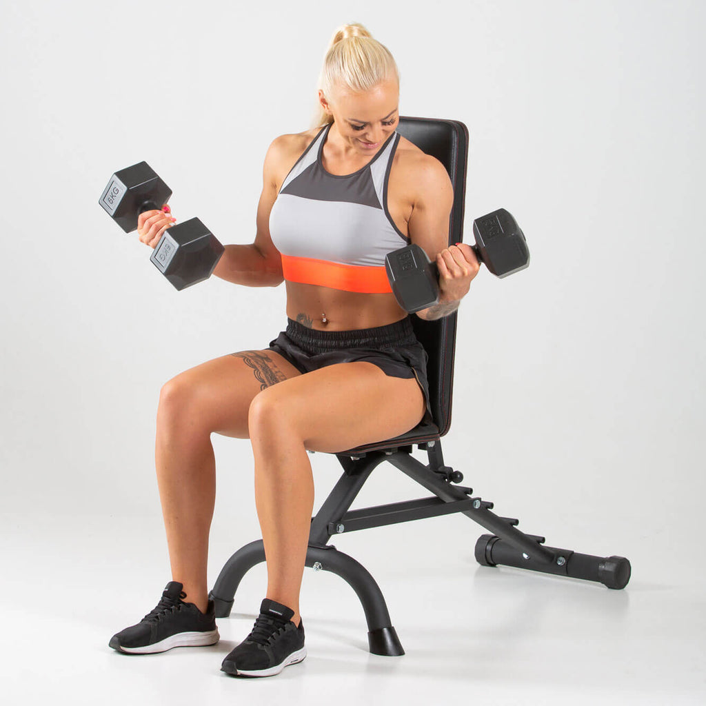 Woman performing bicep curls on a HXGN Ultimate Dumbbell Weight Bench 