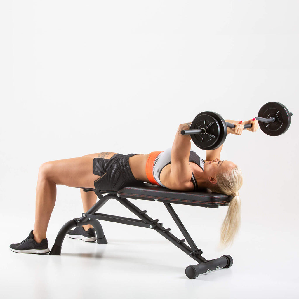 Woman performing Skullcrushers on a HXGN Ultimate Dumbbell Weight Bench 