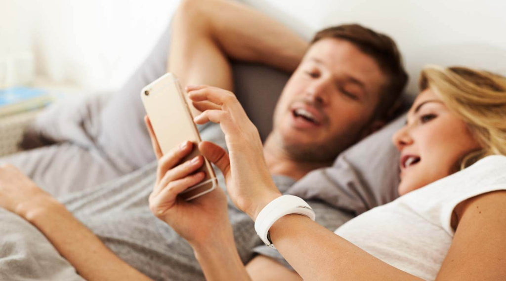 Man woman looking at the Polar app together. Woman is wearing a white Polar Loop 2 Activity Tracker