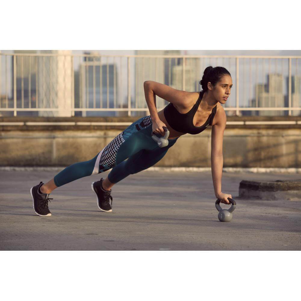Woman performing a kettlebell workout using 2 Reebok 2kg Cast Iron Kettlebells
