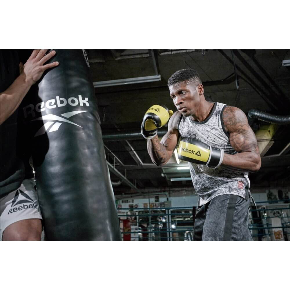 Man punching a Reebok 4ft PU Boxing Punch Bag - Black/White