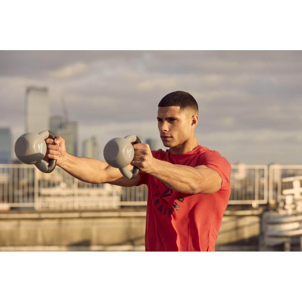 Man performing a kettlebell workout outside using 2 Reebok 6kg Cast Iron Kettlebells