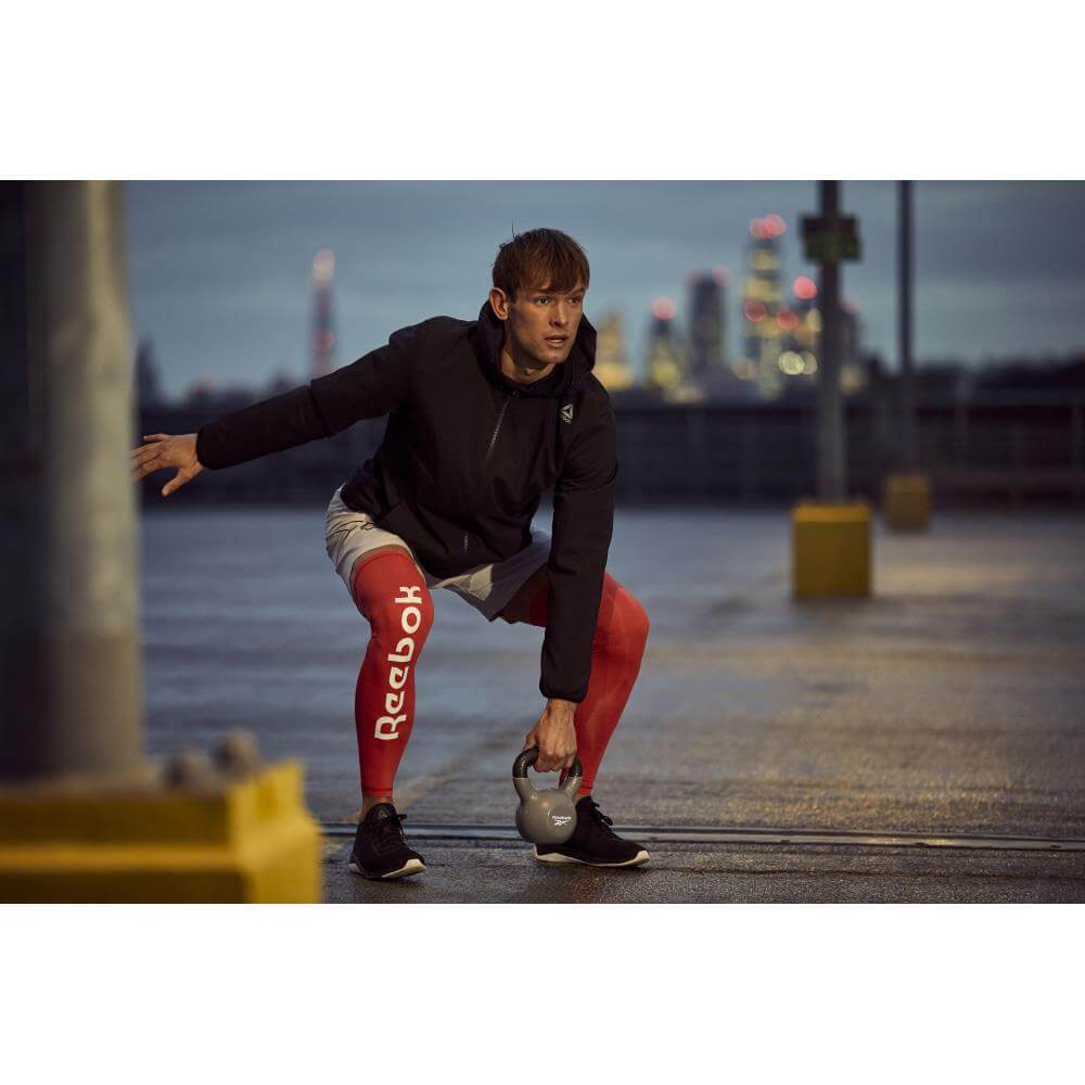 Man performing kettlebell workout outside using a Reebok 6kg Cast Iron Kettlebell