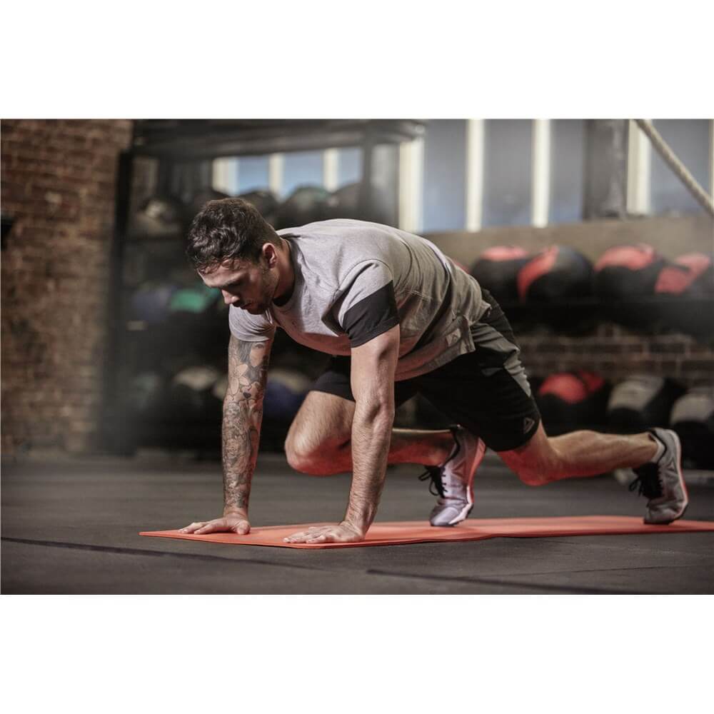 Man working out in the gym on a  red Reebok 7mm Training Mat
