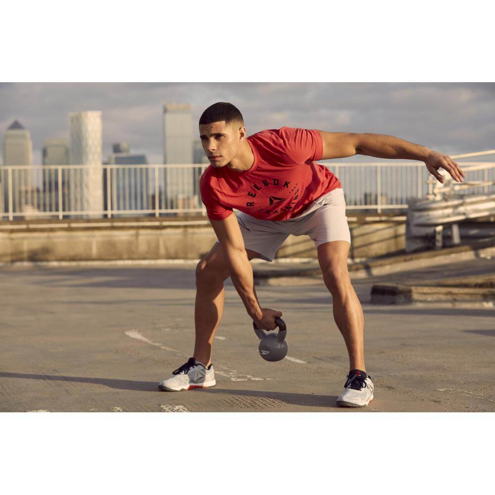 Man performing a kettlebell swing outside using a Reebok 8kg Cast Iron Kettlebell