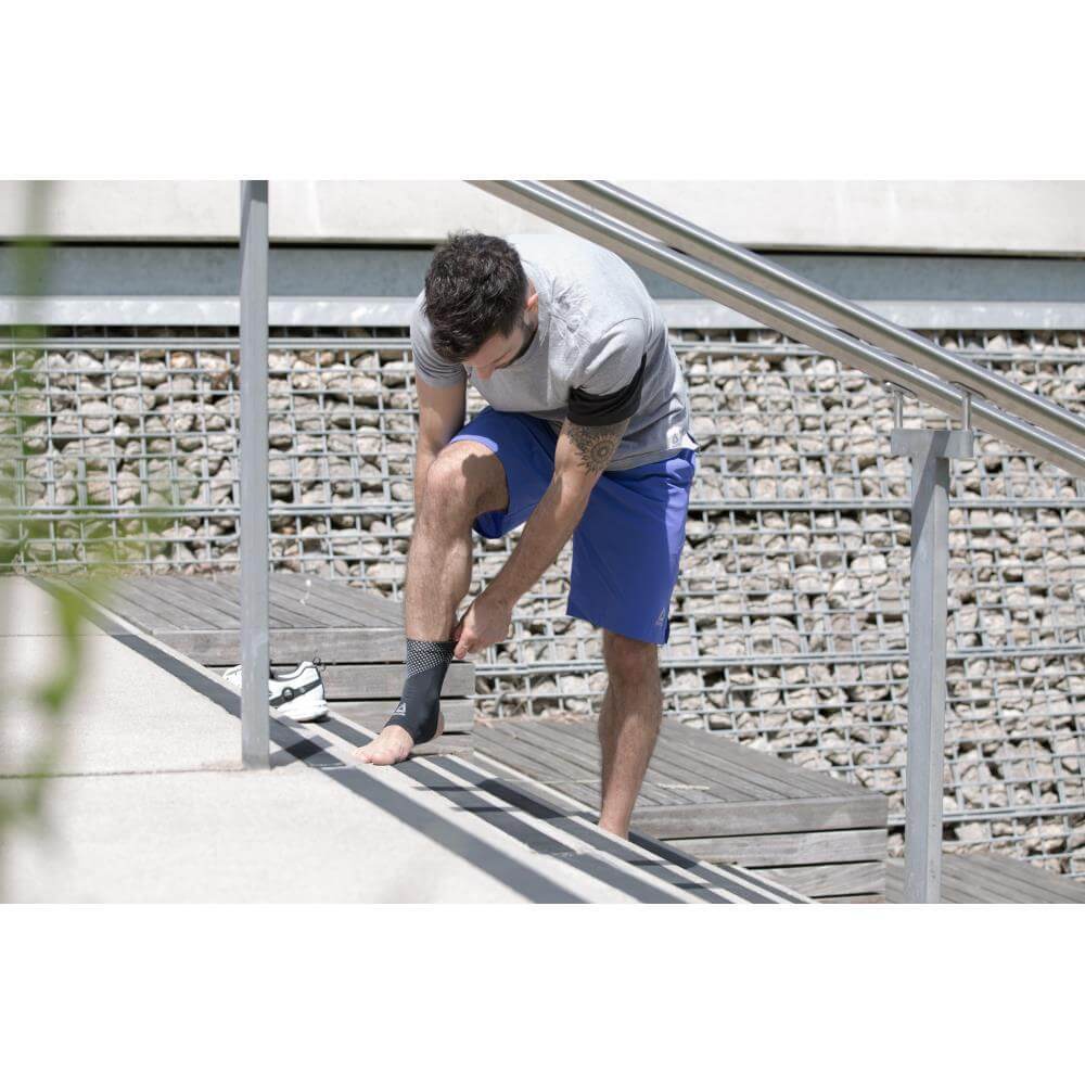 Man on some steps adjusting his Reebok Ankle Support