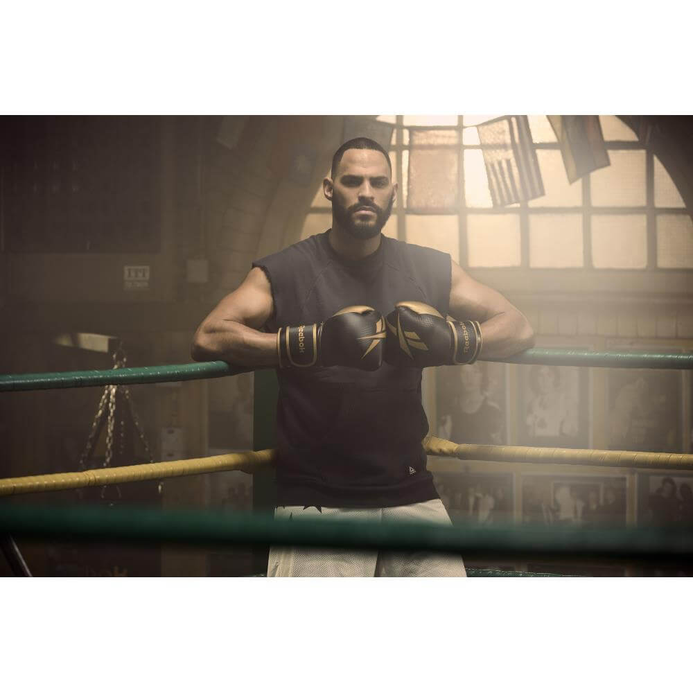 Man in boxing ring wearing a pair of Reebok Boxing Gloves - black/gold
