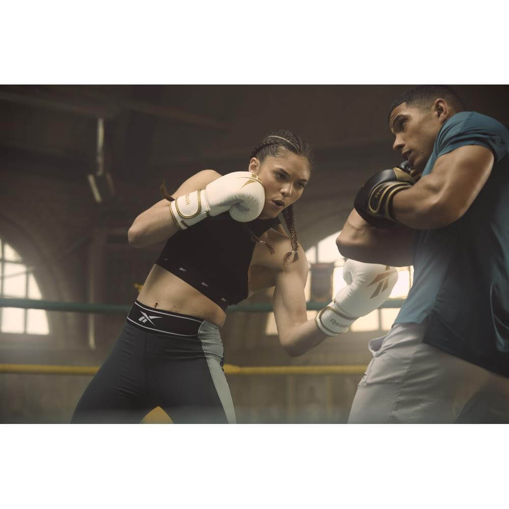 Man and woman punching in boxing ring wearing Reebok Boxing Gloves - White and Gold 