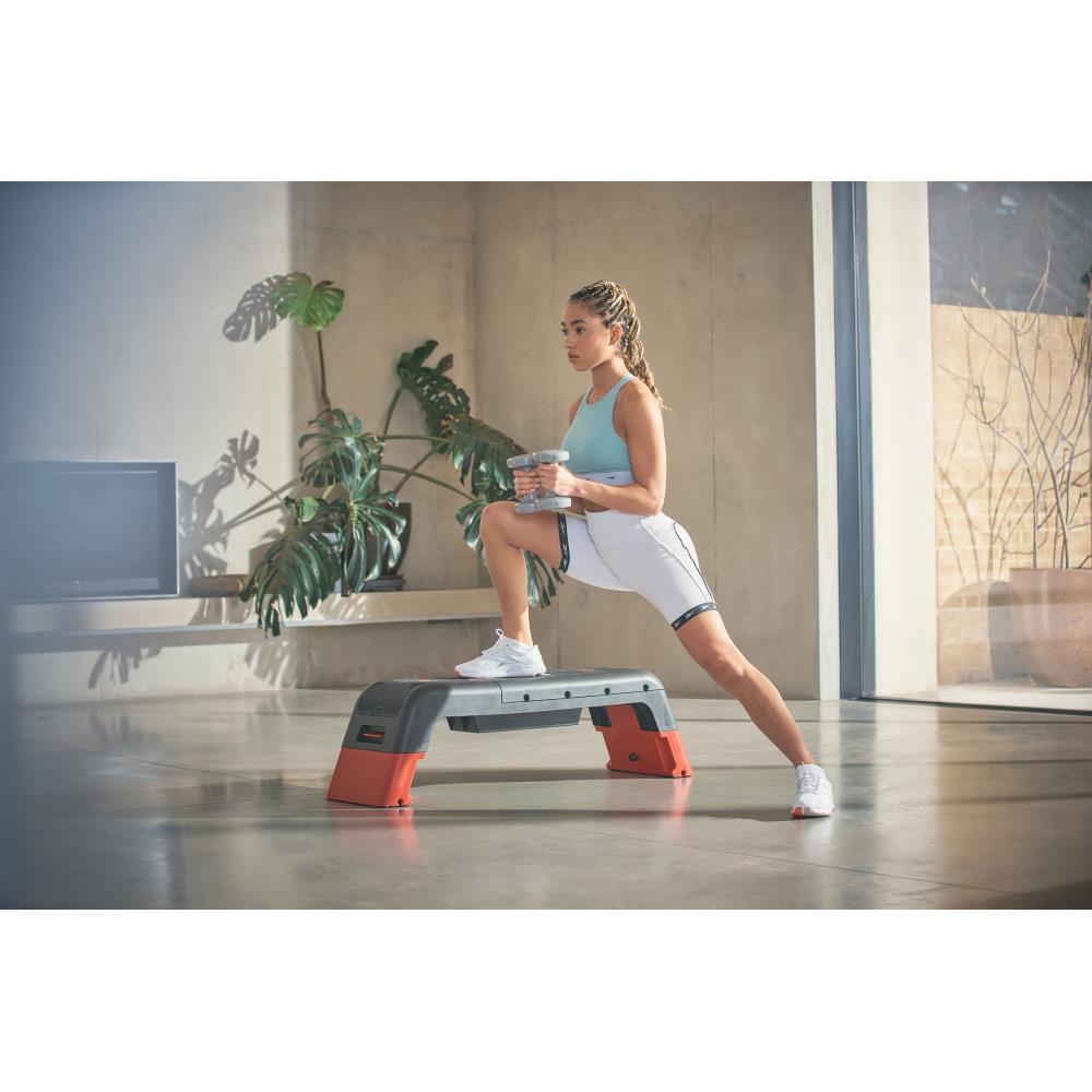 Woman doing a step workout with dumbbells on a Reebok Deck  - Red