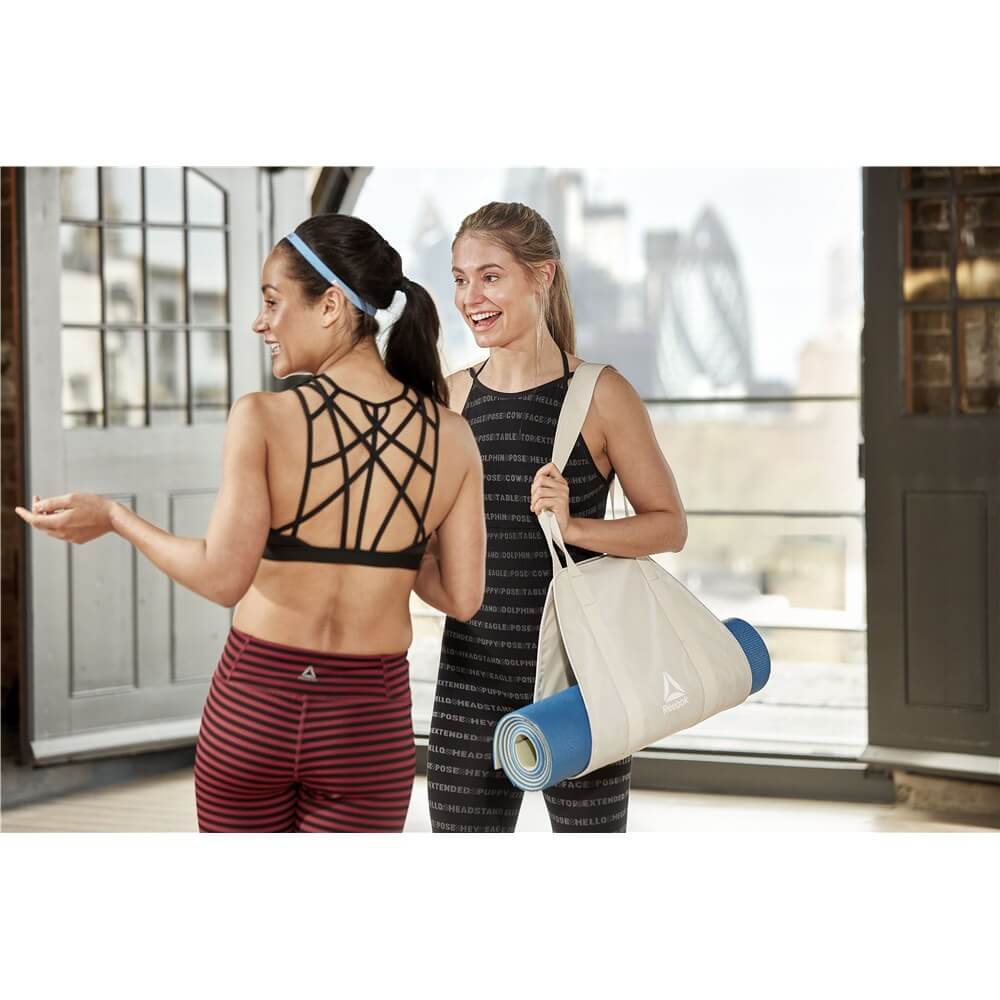 Two women at yoga class holding a Reebok Yoga Mat Carry Sling