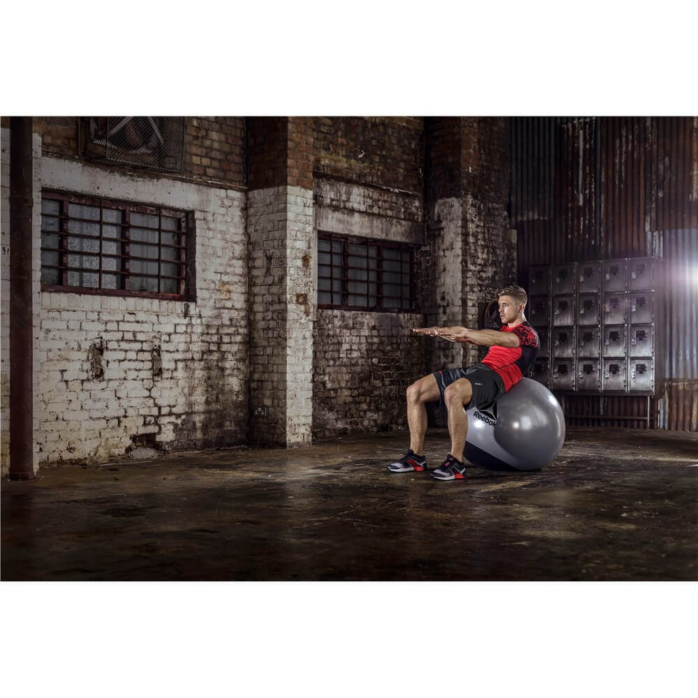 Man exercising on a Reebok Mens Training Stability Gym Ball - 75cm