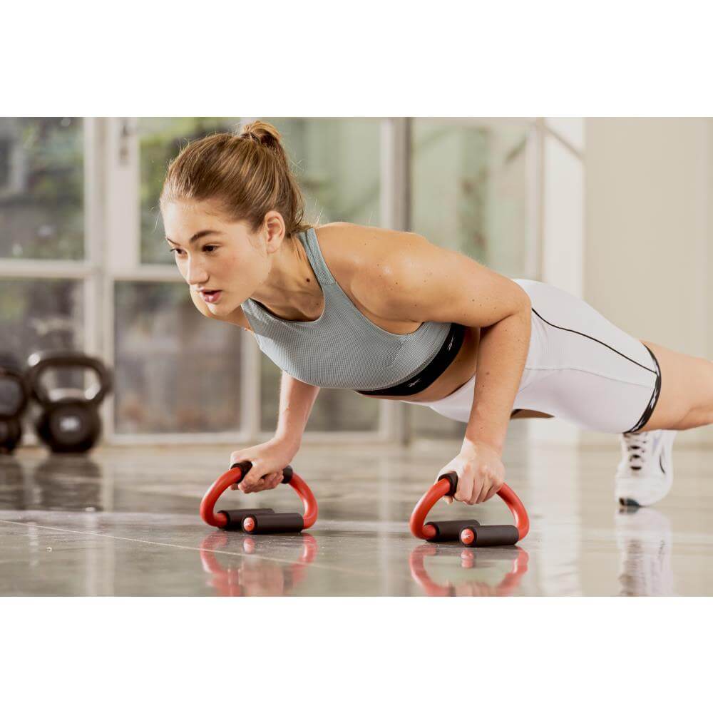 Woman doing push ups using Reebok Push Up Bars in the gym