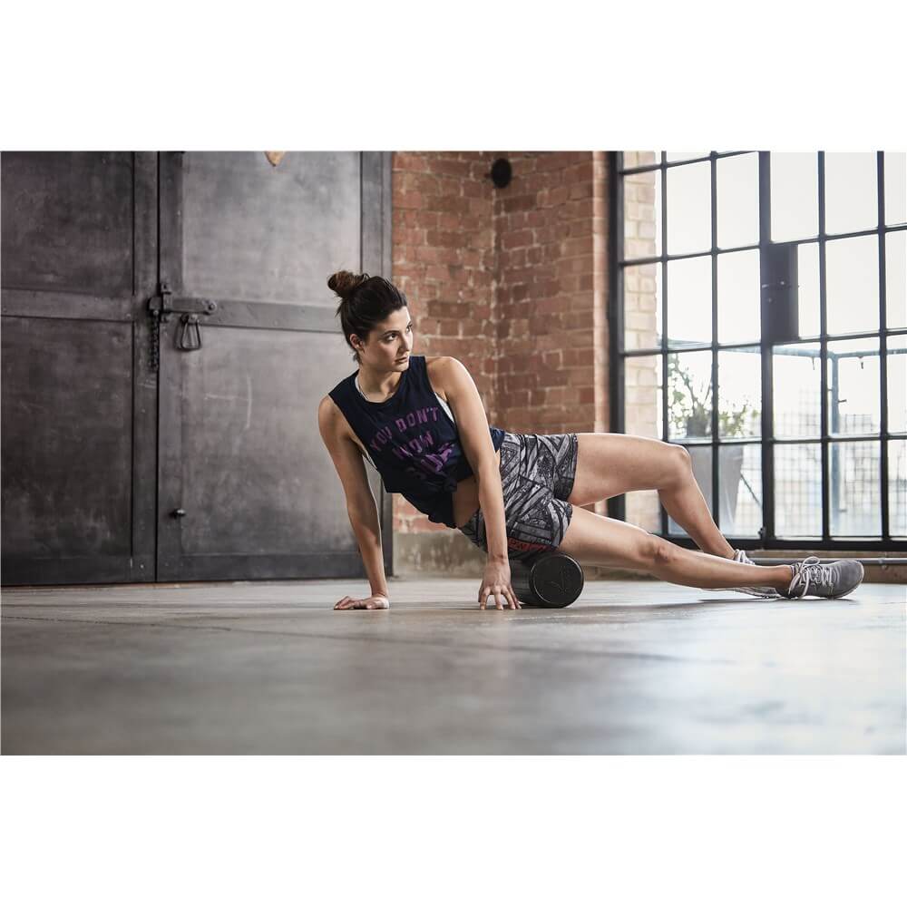 Woman foam rolling using a Reebok Short Foam Roller