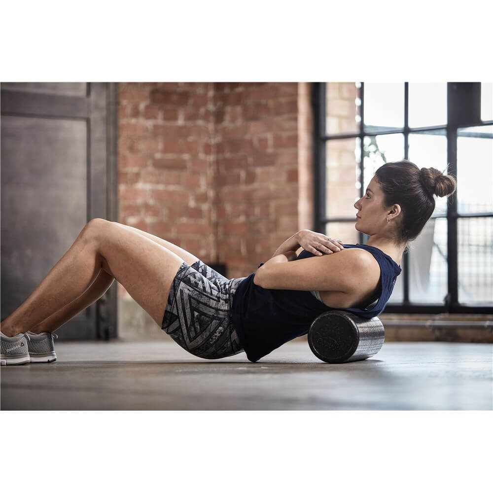 Woman foam rolling using a Reebok Short Foam Roller
